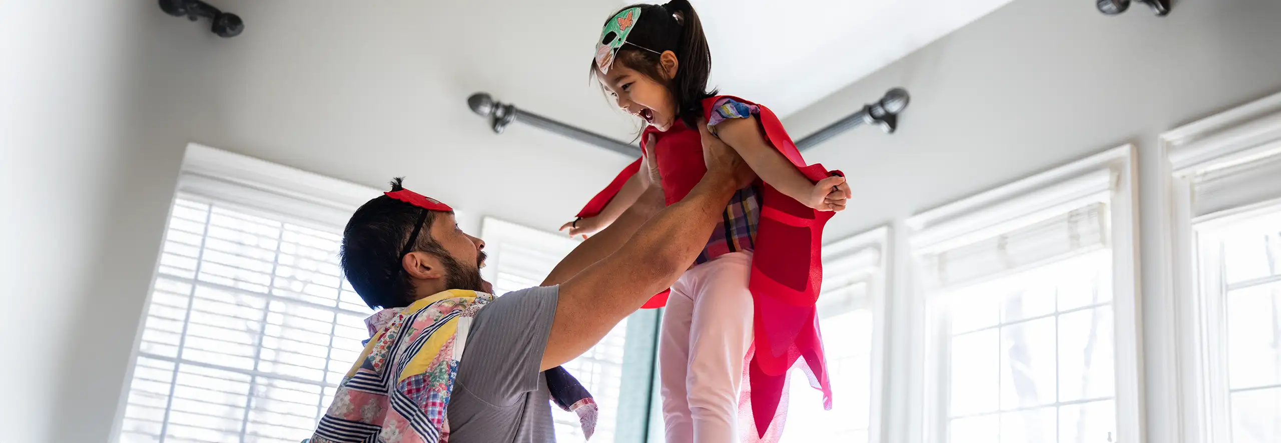 Pai e filha a brincar, com máscaras que eles próprios fizeram