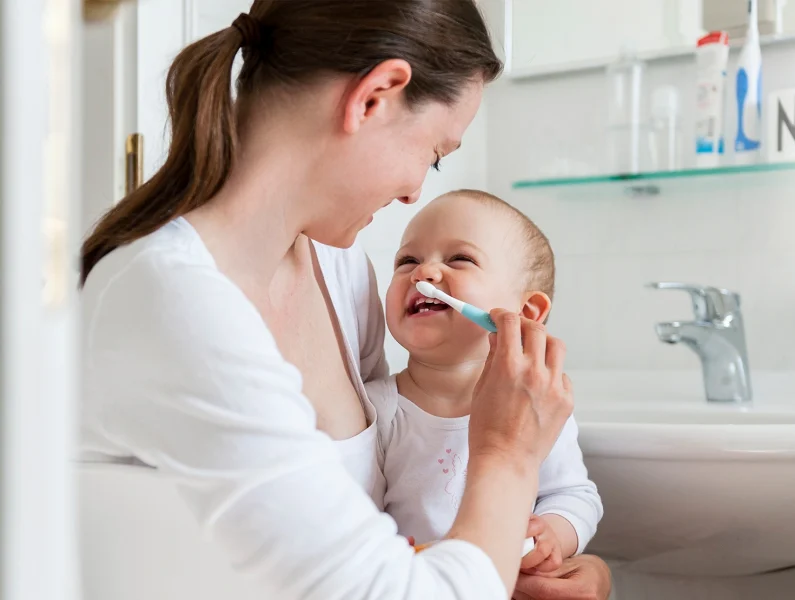 mãe a lavar os dentes do bebé